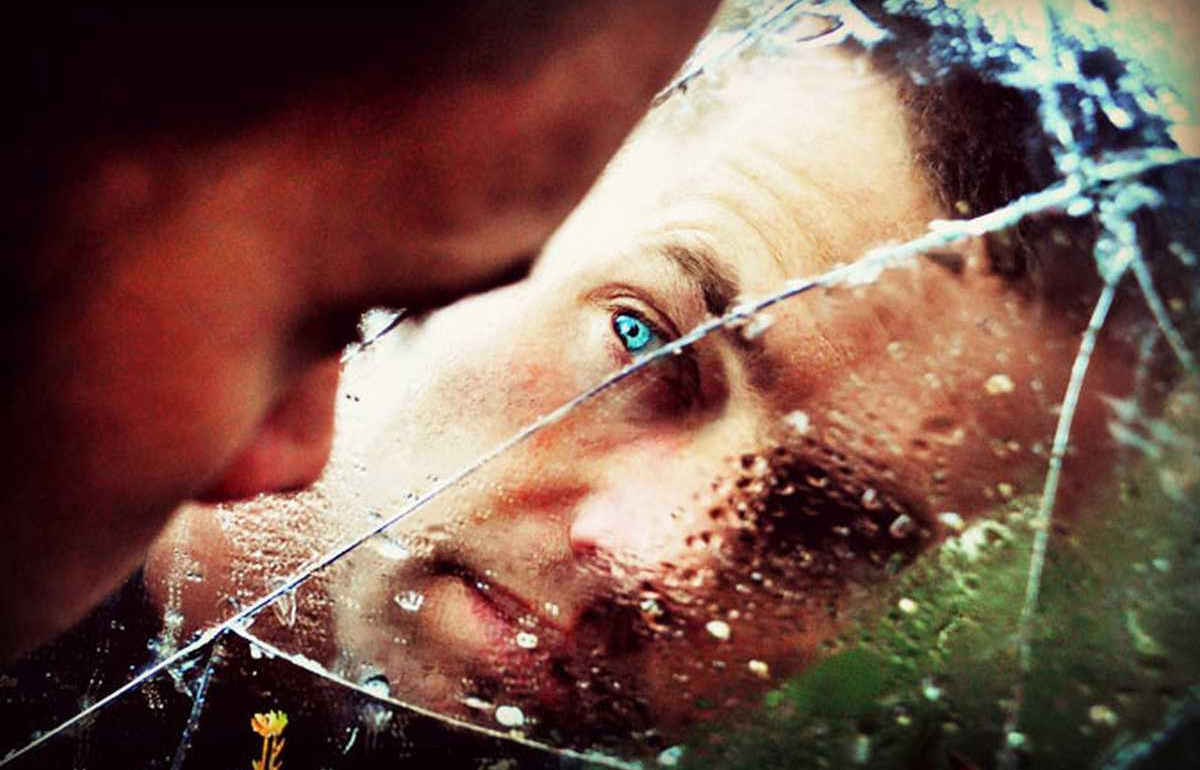 Man staring at his reflection in broken glass mirror, Photofeeler blog header image