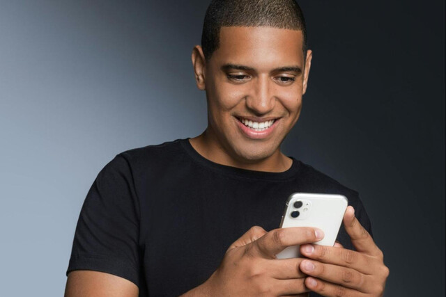 Man smiling while texting on his phone