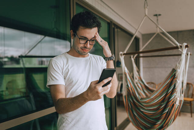confused man looking at his phone in reaction to dating app message